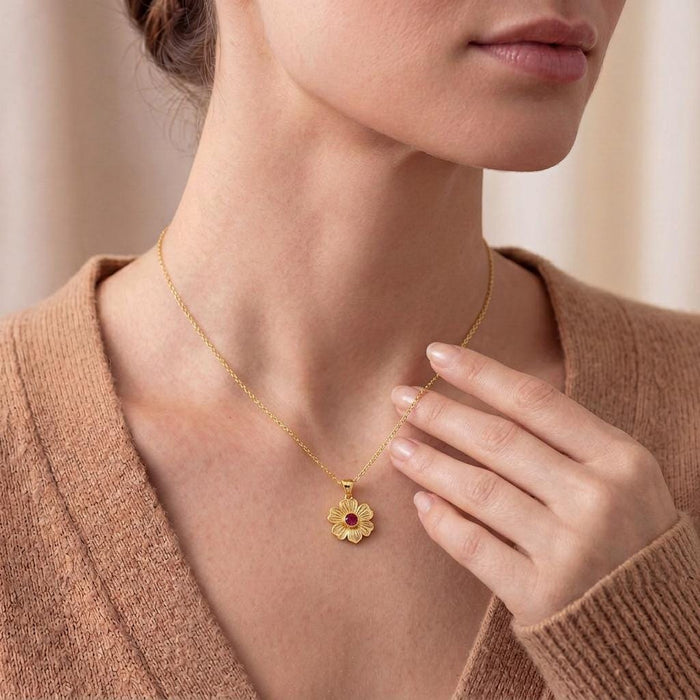 Close neckline view of a Gold Plated Silver Stock Flower Necklace with engraved petals and a red round center stone