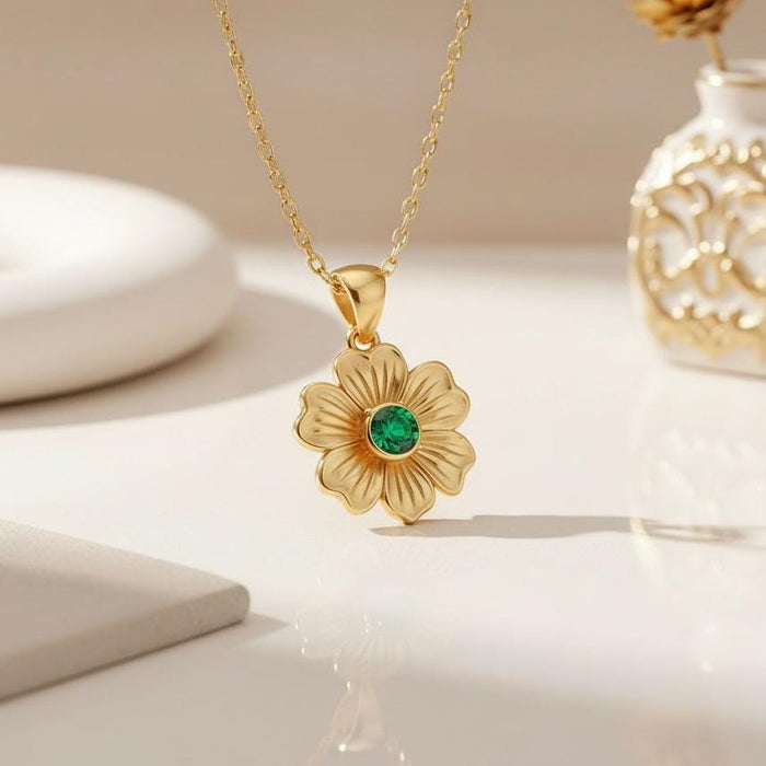 Gold Plated Silver Stock Flower Necklace with engraved petals and a green round center stone on a white surface