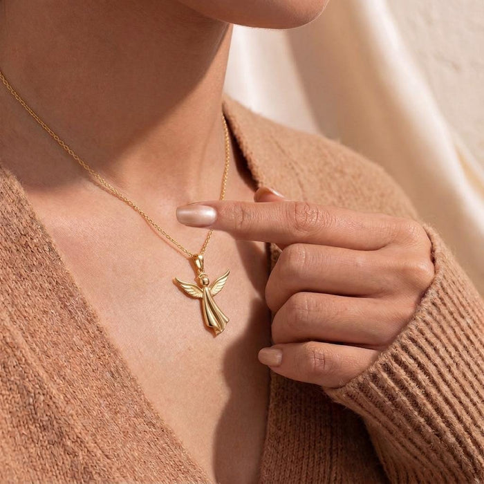 Model pointing to a Gold Plated Silver sculpted angel pendant necklace