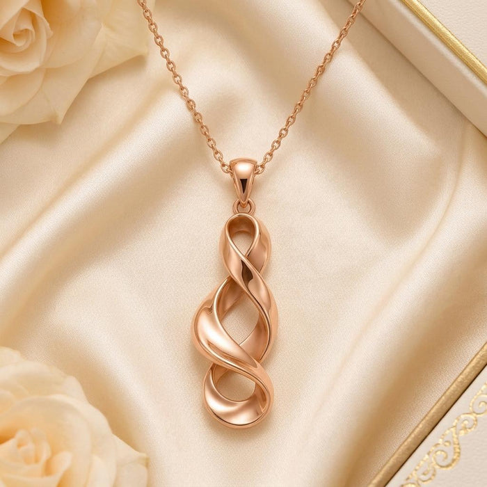 Rose Gold Plated Sculptural Ribbon Necklace with three overlapping open loops on pale satin beside cream roses