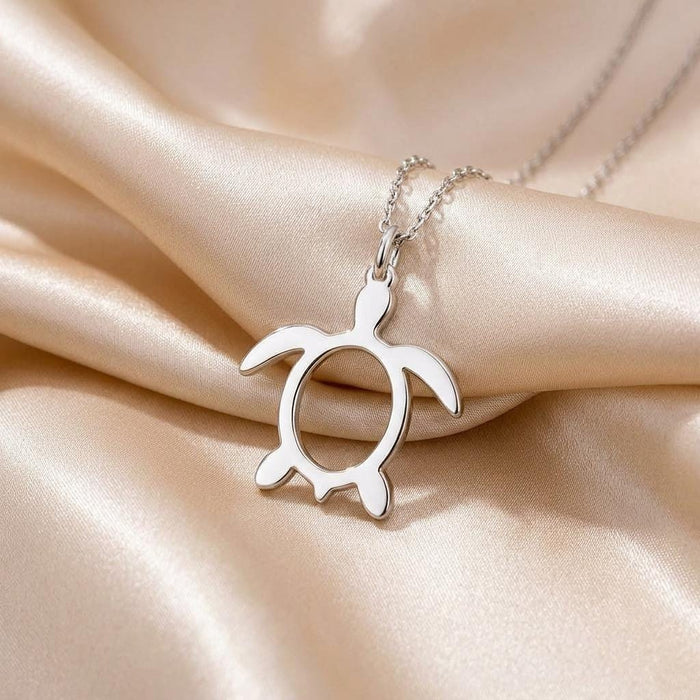 Silver sea turtle pendant necklace displayed on champagne satin