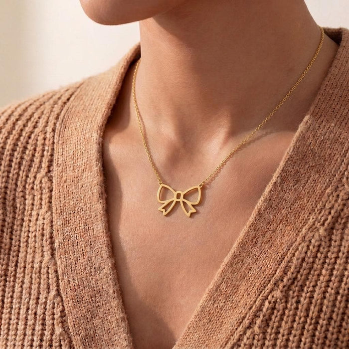 Close neckline view of the Gold Plated Silver Bow Pendant Necklace with textured knitwear