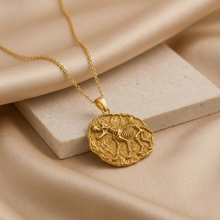 Gold Plated Silver Dire Wolf Fossil Pendant Necklace arranged on beige stone and satin fabric