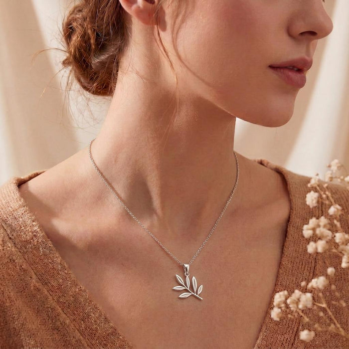 Olive Branch Necklace with a six-leaf pendant worn at the collarbone over a textured knit top