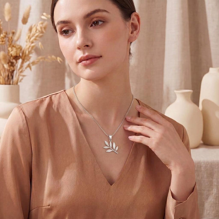 Olive Branch Necklace with a six-leaf pendant worn over a satin V-neck blouse