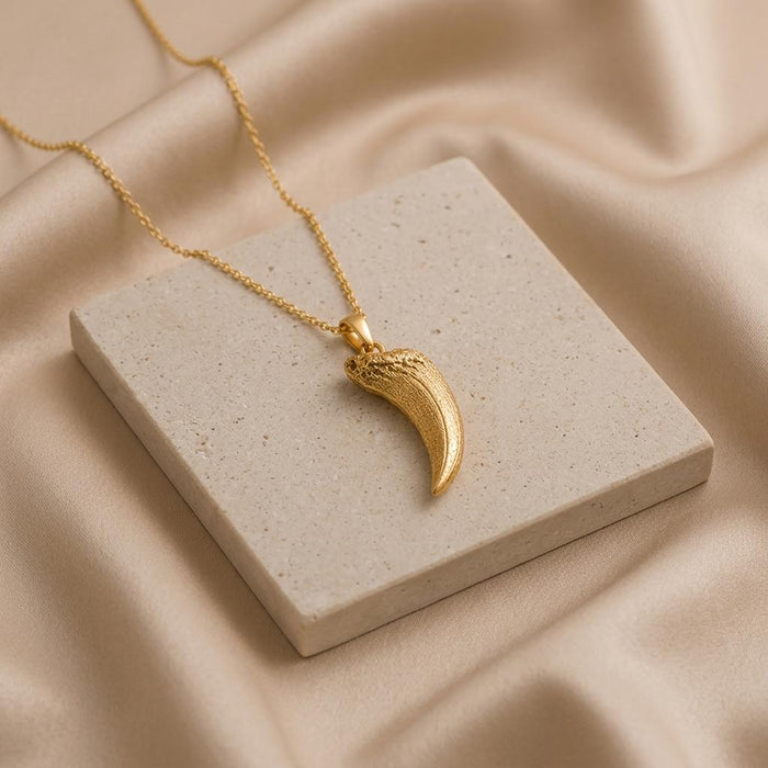 Gold Plated Silver Smilodon fang fossil pendant necklace arranged on a square stone display