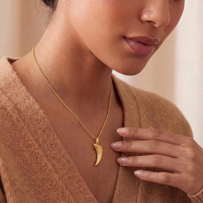 Close view of a Gold Plated Silver Smilodon fang fossil pendant necklace worn with a knit top