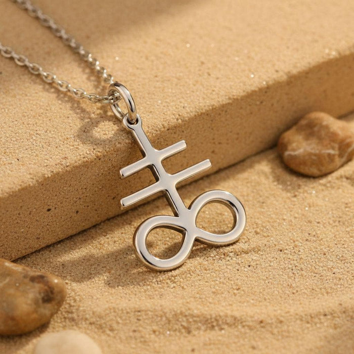 Silver Leviathan Cross pendant with two horizontal bars and an open double-loop base on sand