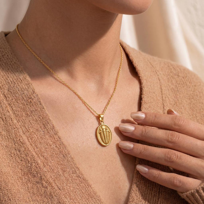Gold Plated Silver trilobite necklace worn with a hand near the pendant