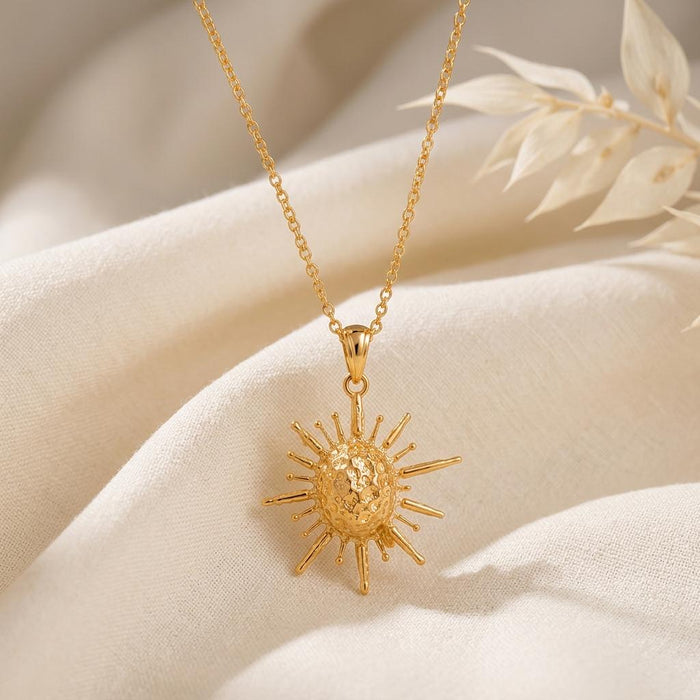 Solar Fragment pendant necklace in Gold Plated Silver displayed on ivory fabric with dried leaves