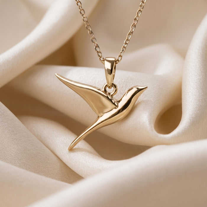 Gold Plated Silver swallow pendant necklace close-up on folded champagne satin