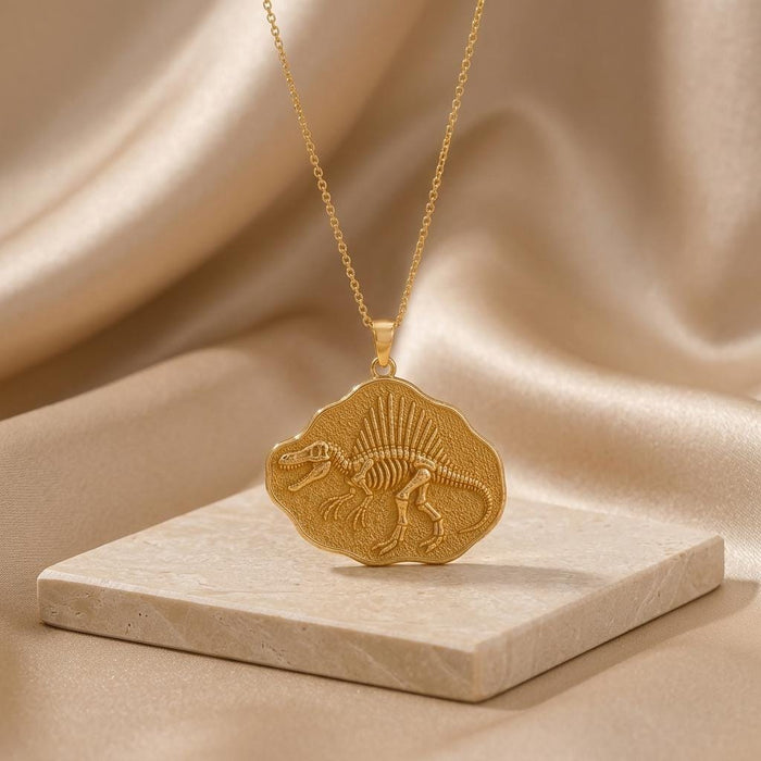 Gold Plated Silver Spinosaurus skeleton medallion necklace on a pale stone display