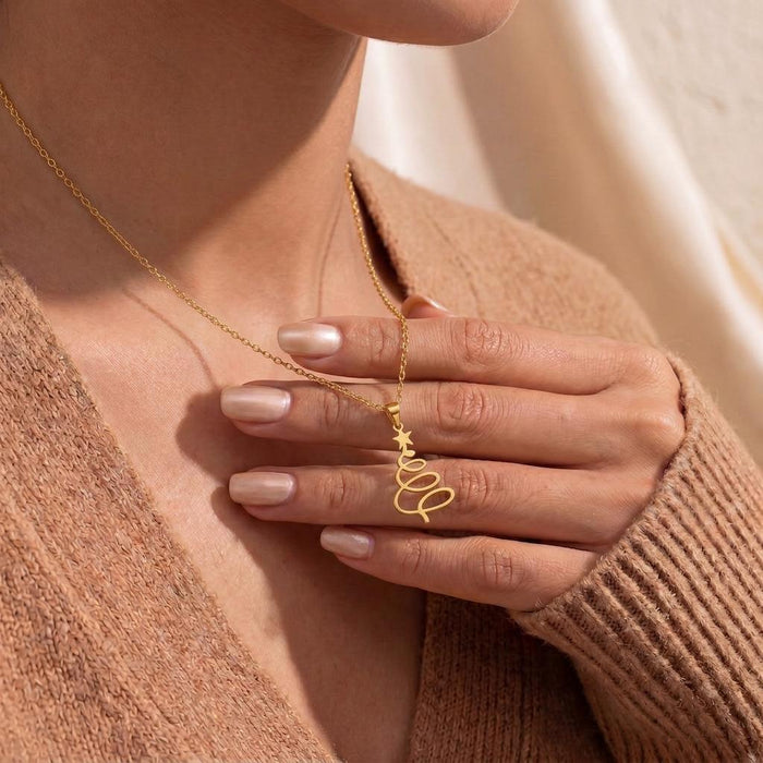 Close view of a Gold Plated Silver spiral Christmas tree pendant held against a brown knit top