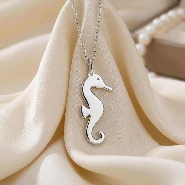 Close-up of a polished seahorse pendant on cream fabric