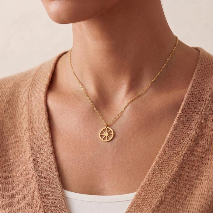 Gold Plated Silver Sun Symbol Necklace with round wheel pendant worn above a white camisole