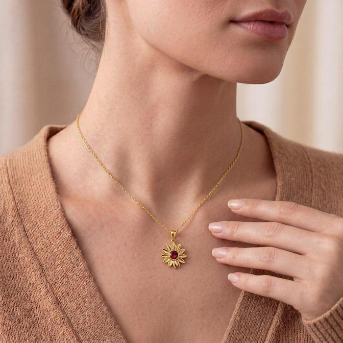 Neckline view of a model wearing a Gold Plated Silver sunflower pendant necklace with a red center detail and tan knit top