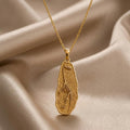 Gold Plated Silver Tanystropheus fossil pendant necklace with raised skeleton relief on champagne satin