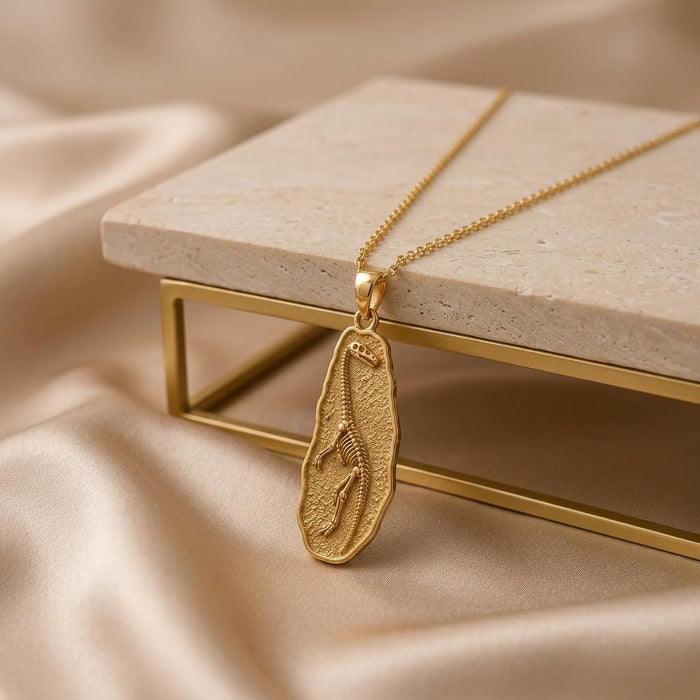 Gold Plated Silver Tanystropheus fossil pendant necklace beside a raised stone display