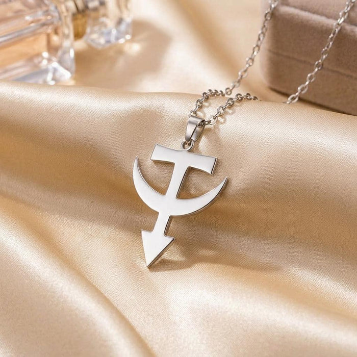 Polished Tataria symbol pendant displayed on ivory satin beside jewelry boxes