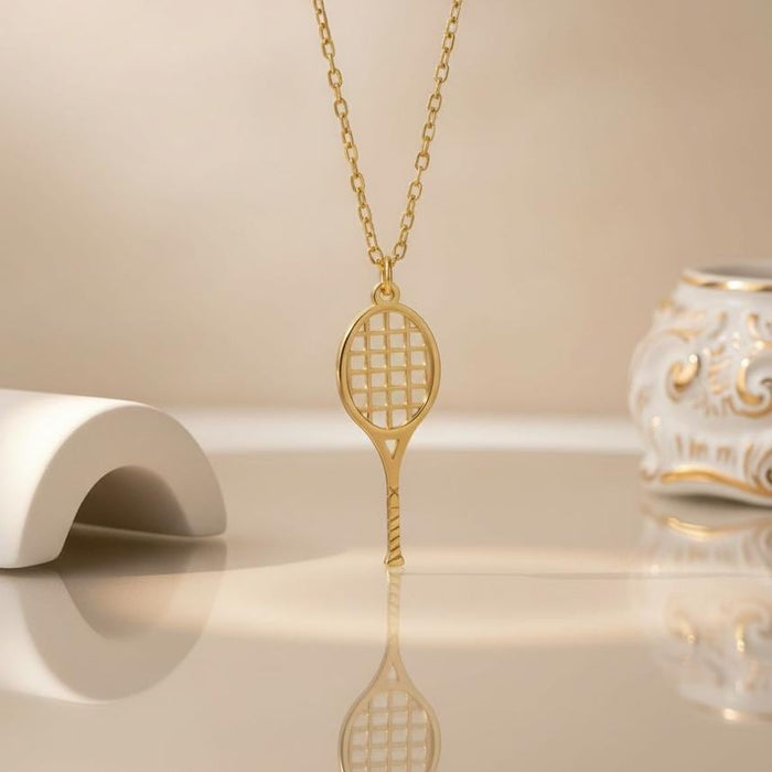 Gold Plated Silver Tennis Racket Necklace standing upright on a reflective cream display surface