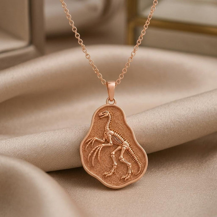 Rose Gold Plated Therizinosaurus skeleton fossil pendant close-up on beige satin
