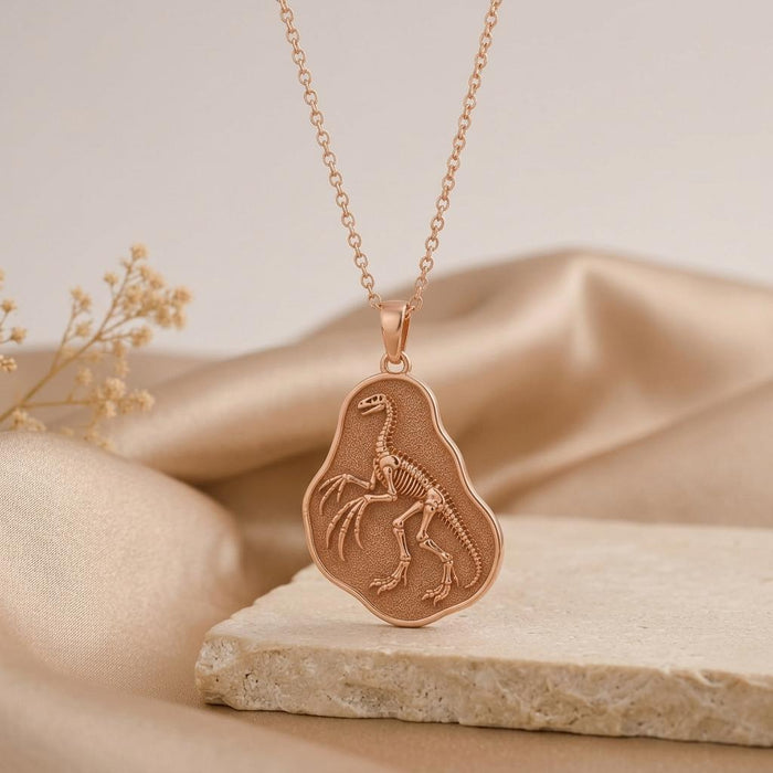 Rose Gold Plated Therizinosaurus skeleton pendant displayed on a natural stone surface