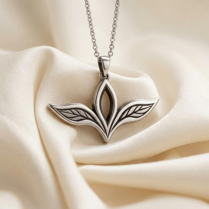 Elven Leaf Necklace displayed on ivory fabric, showing the upright open center leaf and outward-facing engraved side leaves.