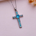 Turquoise cross necklace with turquoise inlay arms and a round blue center stone on pale fabric