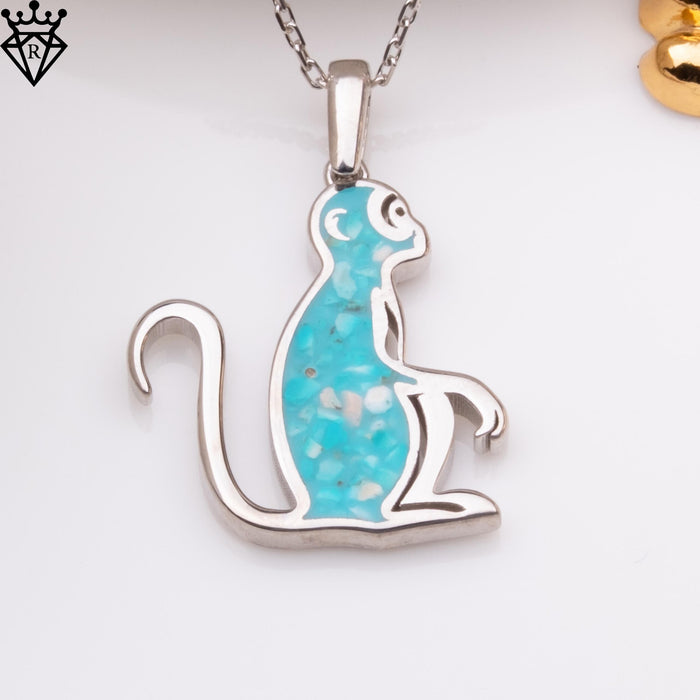 Seated turquoise monkey pendant with a long curled tail, shown close up on white