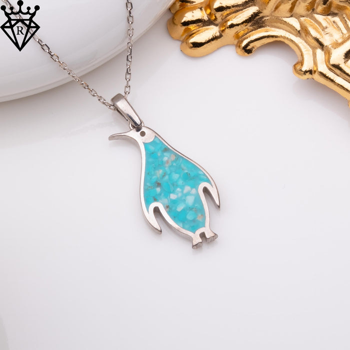 Angled penguin necklace displayed beside white and gold decorative objects