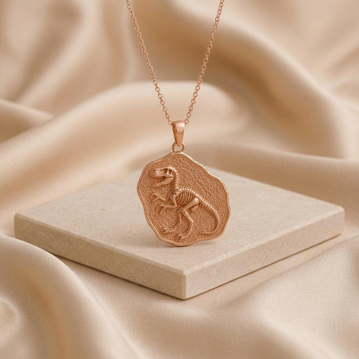 Rose Gold Plated Velociraptor Fossil Pendant displayed upright on a pale stone block with satin