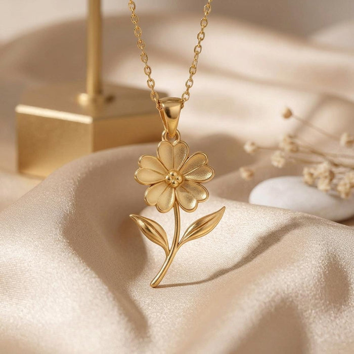Gold Plated Silver Verbena flower pendant on cream satin beside a jewelry display stand