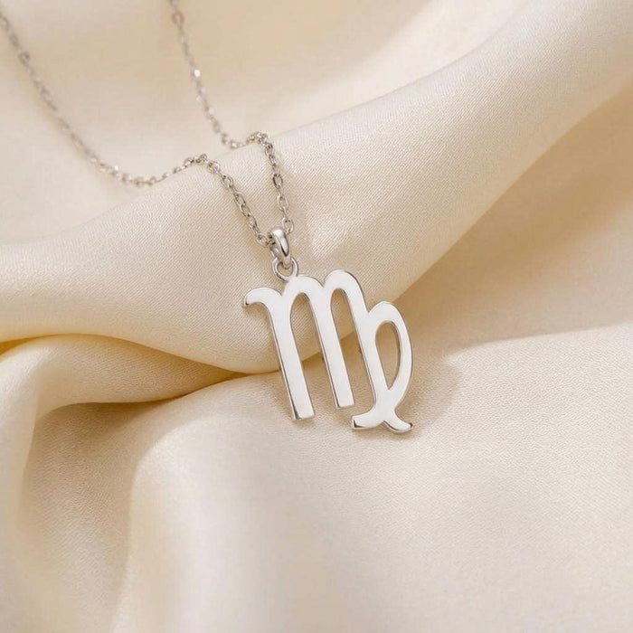Close-up of polished Virgo glyph pendant necklace on cream satin