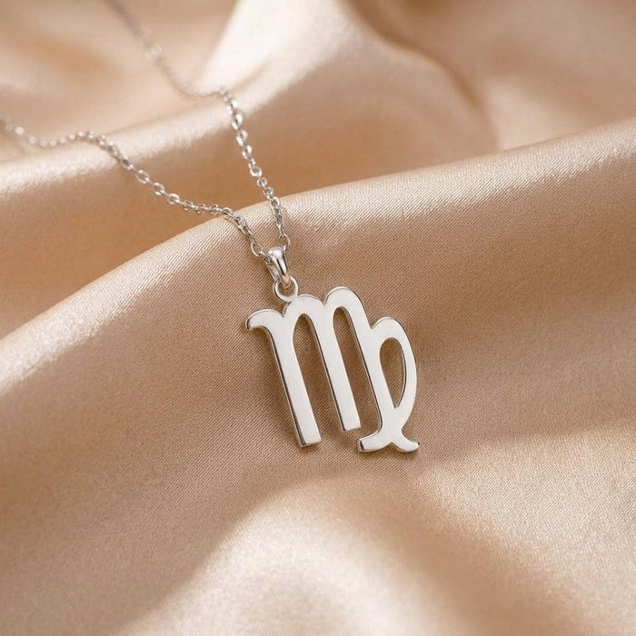 Detailed Virgo glyph pendant necklace displayed on draped cream satin