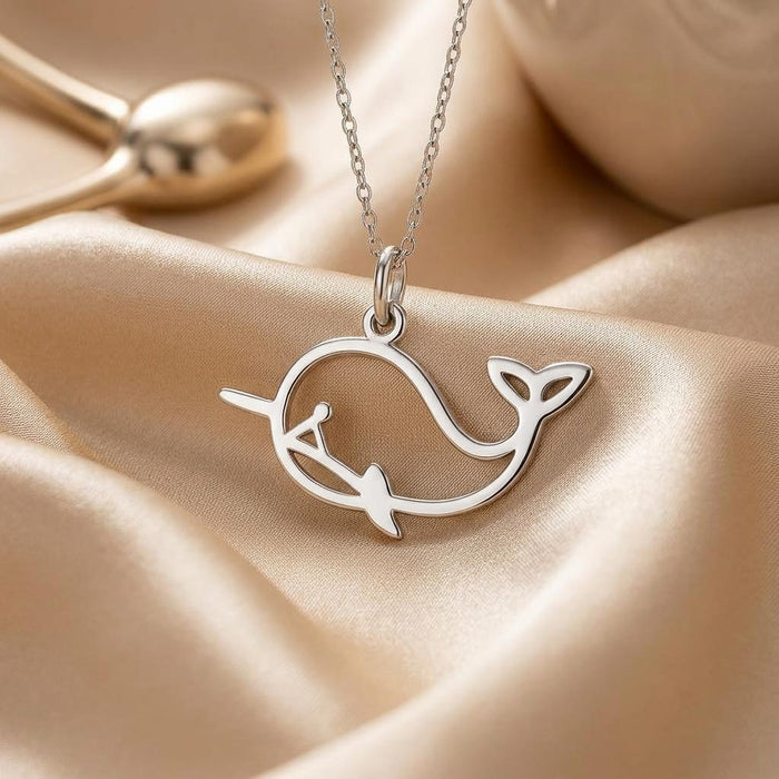 Close-up of the whale outline pendant on champagne-colored satin