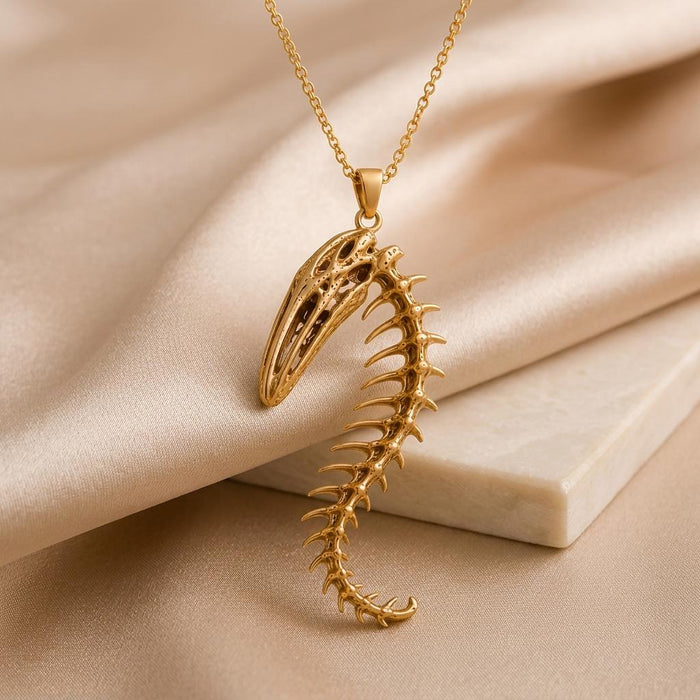 Gold Plated Silver Whale Spine Relic pendant necklace on champagne satin beside a pale stone block