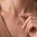 Gold Plated Silver Wishbone Necklace worn at the collarbone with a hand touching the open forked pendant