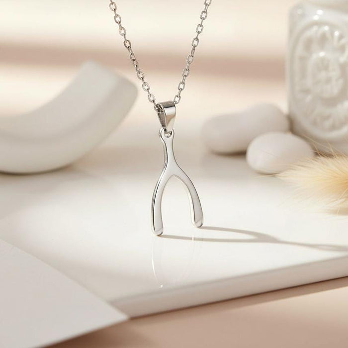 Silver Wishbone Necklace displayed upright on a white ceramic surface